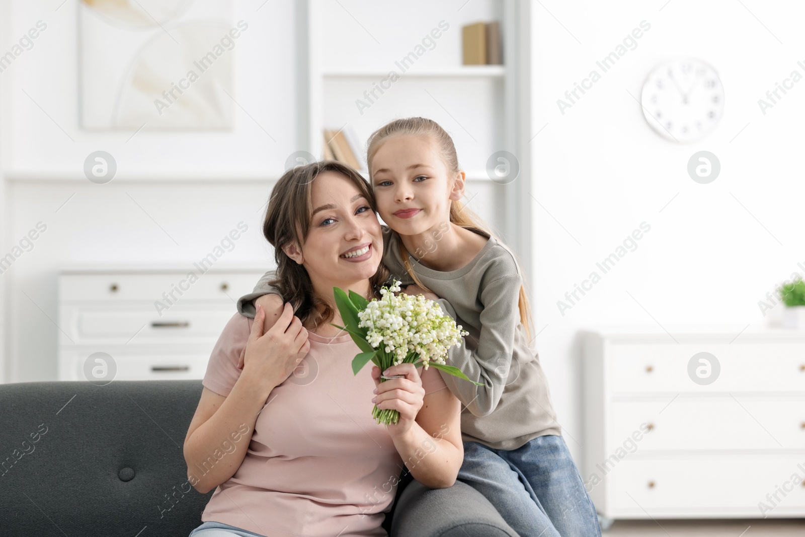 Girl giving her mother beautiful bouquet of lily-of-the-valley flowers at home Photo of Girl giving her mother beautiful bouquet of lily-of-the-valley flowers at home