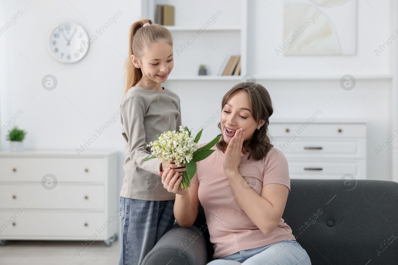Girl giving her mother beautiful bouquet of lily-of-the-valley flowers at home Photo of Girl giving her mother beautiful bouquet of lily-of-the-valley flowers at home