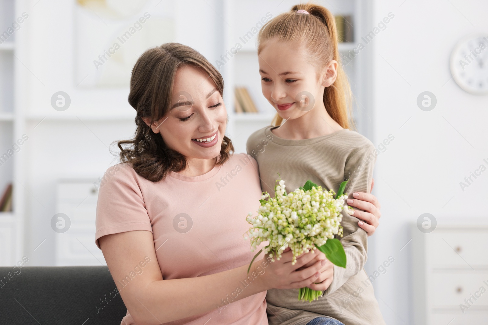 Girl giving her mother beautiful bouquet of lily-of-the-valley flowers at home Photo of Girl giving her mother beautiful bouquet of lily-of-the-valley flowers at home