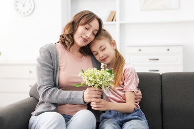 Photo of Girl giving her mother beautiful bouquet of lily-of-the-valley flowers at home