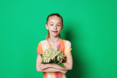 Photo of Girl with bouquet of beautiful lily-of-the-valley flowers on green background