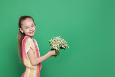 Photo of Girl with bouquet of beautiful lily-of-the-valley flowers on green background. Space for text