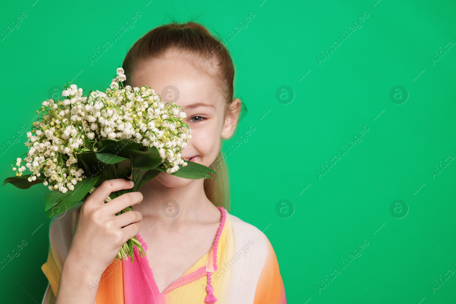 Girl with bouquet of beautiful lily-of-the-valley flowers on green background. Space for text Photo of Girl with bouquet of beautiful lily-of-the-valley flowers on green background. Space for text