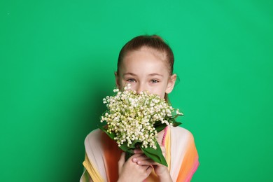 Photo of Girl with bouquet of beautiful lily-of-the-valley flowers on green background