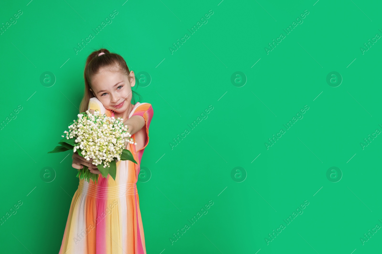 Girl with bouquet of beautiful lily-of-the-valley flowers on green background. Space for text Photo of Girl with bouquet of beautiful lily-of-the-valley flowers on green background. Space for text