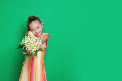 Photo of Girl with bouquet of beautiful lily-of-the-valley flowers on green background. Space for text