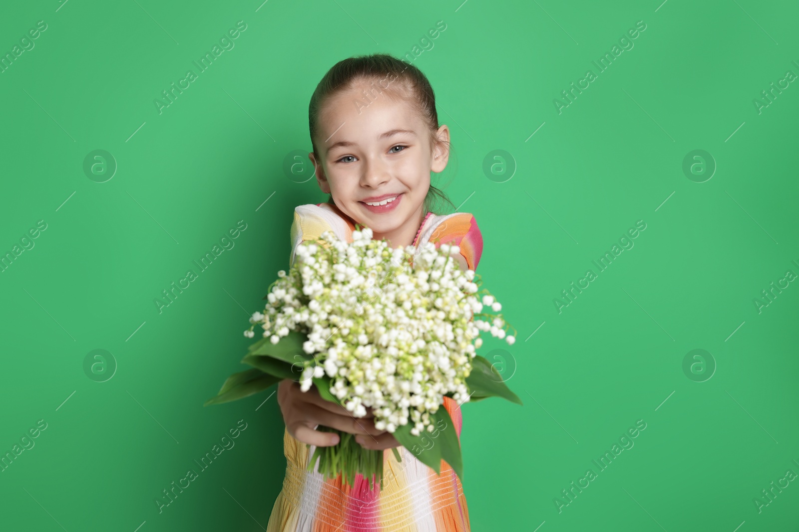 Girl with bouquet of beautiful lily-of-the-valley flowers on green background Photo of Girl with bouquet of beautiful lily-of-the-valley flowers on green background
