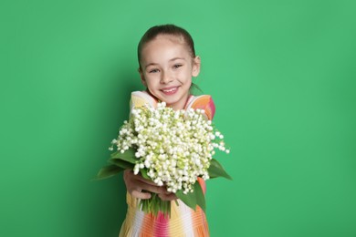 Photo of Girl with bouquet of beautiful lily-of-the-valley flowers on green background