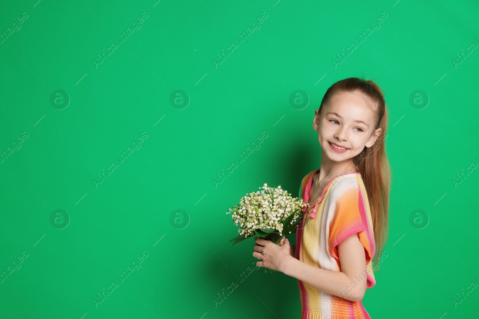 Girl with bouquet of beautiful lily-of-the-valley flowers on green background. Space for text Photo of Girl with bouquet of beautiful lily-of-the-valley flowers on green background. Space for text