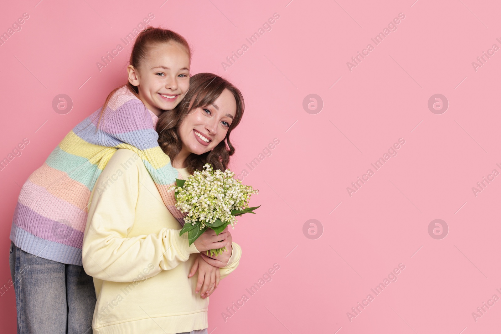 Girl giving her mother beautiful bouquet of lily-of-the-valley flowers on light pink background. Space for text Photo of Girl giving her mother beautiful bouquet of lily-of-the-valley flowers on light pink background. Space for text