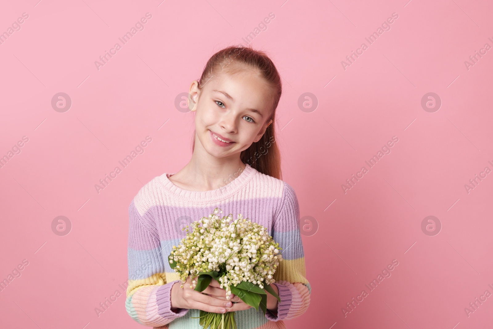 Girl with bouquet of beautiful lily-of-the-valley flowers on light pink background Photo of Girl with bouquet of beautiful lily-of-the-valley flowers on light pink background