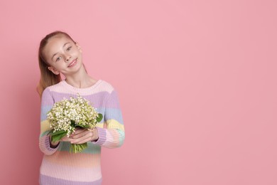 Photo of Girl with bouquet of beautiful lily-of-the-valley flowers on light pink background. Space for text