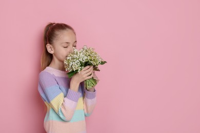 Photo of Girl with bouquet of beautiful lily-of-the-valley flowers on light pink background. Space for text