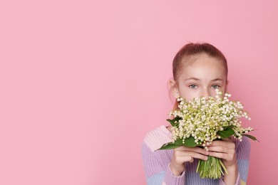 Photo of Girl with bouquet of beautiful lily-of-the-valley flowers on light pink background. Space for text