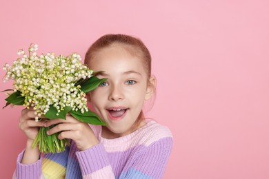 Photo of Girl with bouquet of beautiful lily-of-the-valley flowers on light pink background. Space for text