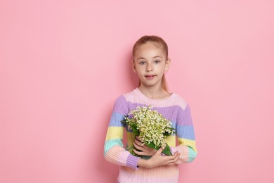 Photo of Girl with bouquet of beautiful lily-of-the-valley flowers on light pink background. Space for text