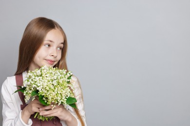 Photo of Girl with bouquet of beautiful lily-of-the-valley flowers on light grey background. Space for text