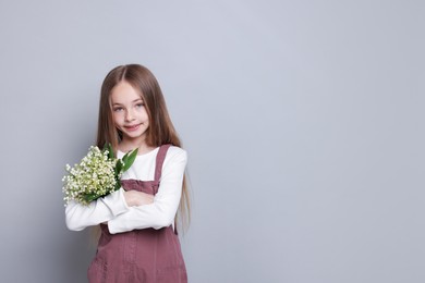 Photo of Girl with bouquet of beautiful lily-of-the-valley flowers on light grey background. Space for text
