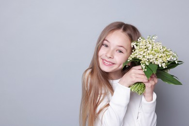 Photo of Girl with bouquet of beautiful lily-of-the-valley flowers on light grey background. Space for text