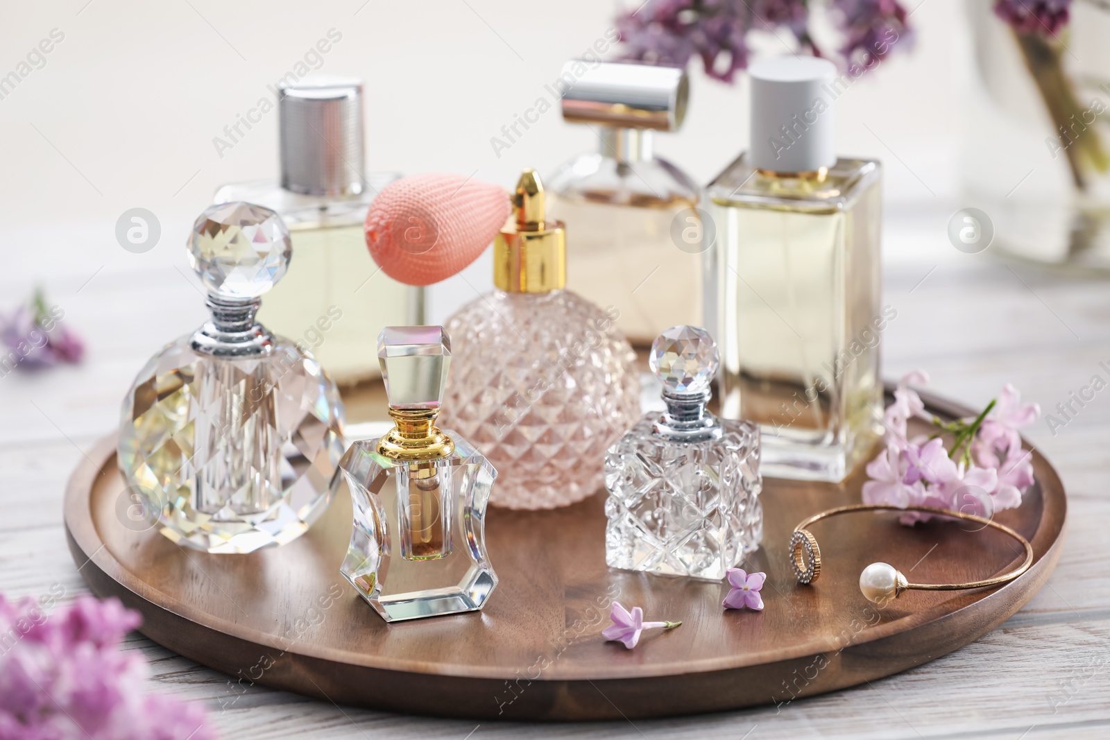Bottles of perfumes and lilac flowers on white wooden table, closeup Photo of Bottles of perfumes and lilac flowers on white wooden table, closeup
