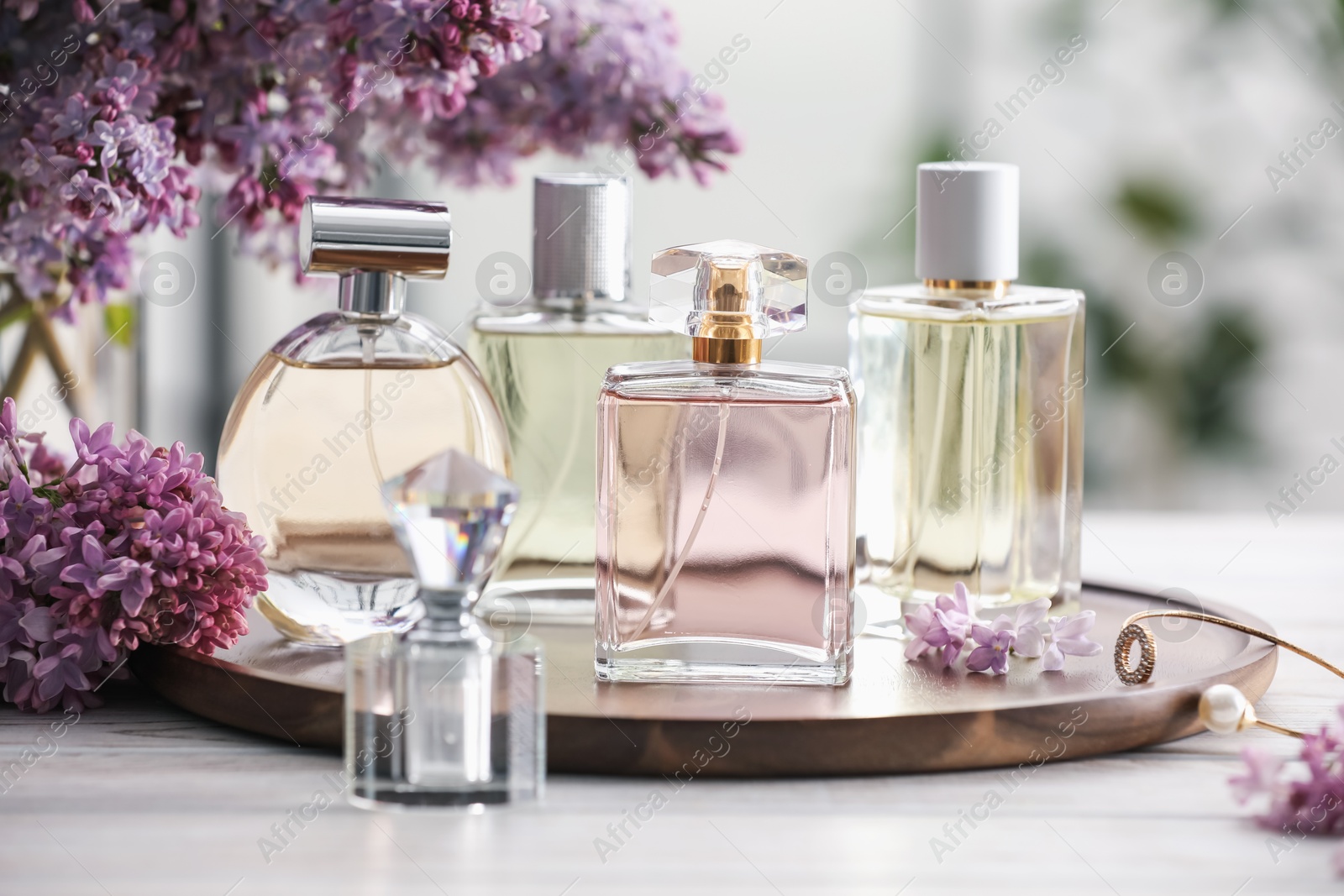 Bottles of perfumes and lilac flowers on white wooden table, closeup Photo of Bottles of perfumes and lilac flowers on white wooden table, closeup
