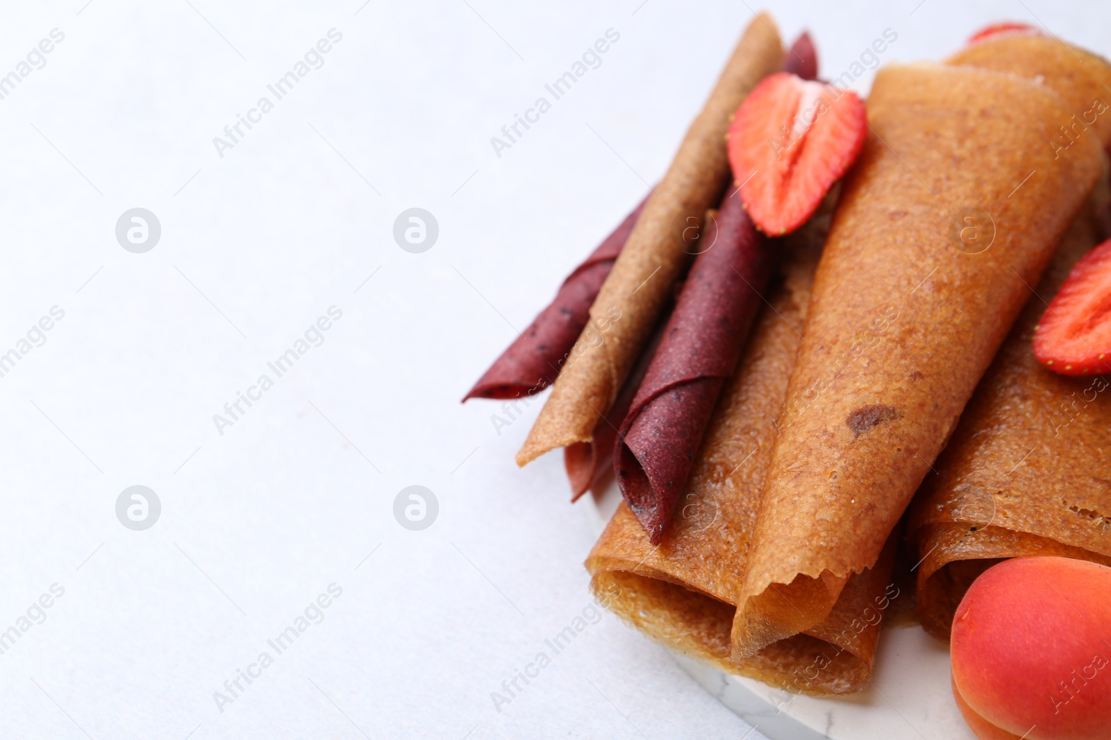 Delicious fruit leather rolls, strawberry and apricot on light table, closeup. Space for text Photo of Delicious fruit leather rolls, strawberry and apricot on light table, closeup. Space for text