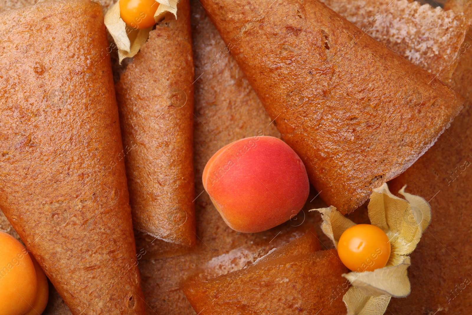 Delicious fruit leather rolls, apricots and physalis as background, top view Photo of Delicious fruit leather rolls, apricots and physalis as background, top view
