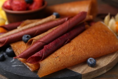 Photo of Delicious fruit leather rolls and berries on table, closeup