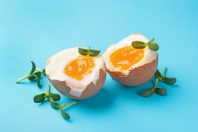 Photo of Soft boiled eggs with microgreens on light blue background, closeup