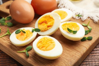 Photo of Halves of hard boiled eggs with microgreens on wooden table, closeup