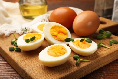 Photo of Halves of hard boiled eggs with microgreens on wooden table, closeup