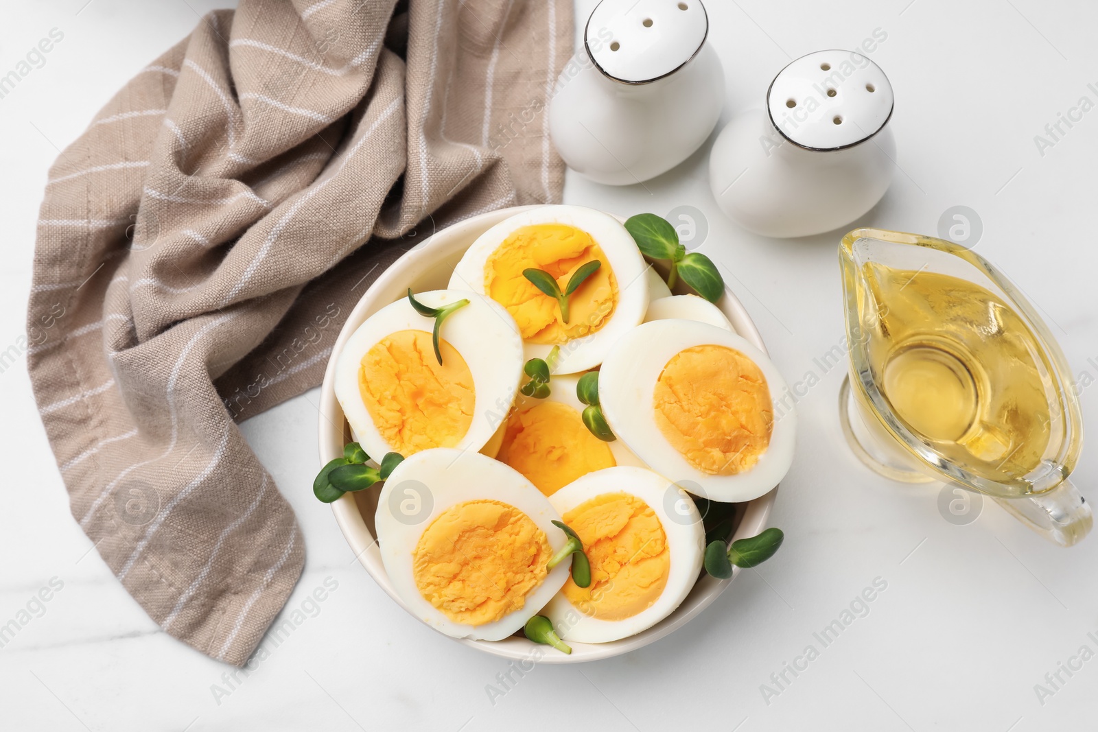 Halves of hard boiled eggs with microgreens on white table, flat lay Photo of Halves of hard boiled eggs with microgreens on white table, flat lay