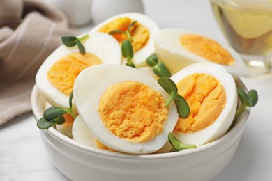 Photo of Halves of hard boiled eggs with microgreens on white table, closeup