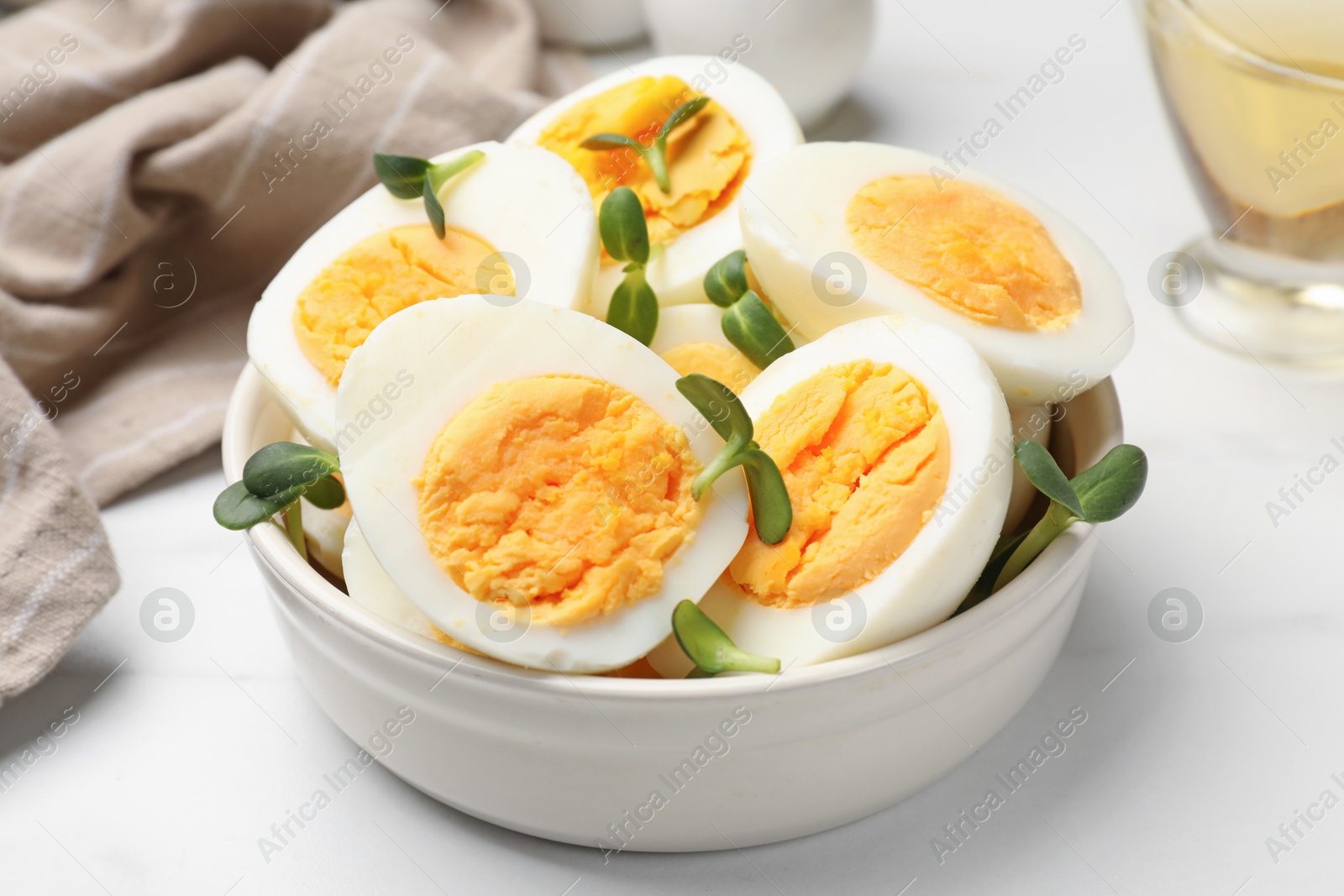 Photo of Halves of hard boiled eggs with microgreens on white table, closeup