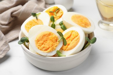 Photo of Halves of hard boiled eggs with microgreens on white table, closeup