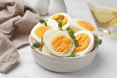 Photo of Halves of hard boiled eggs with microgreens on white table, closeup