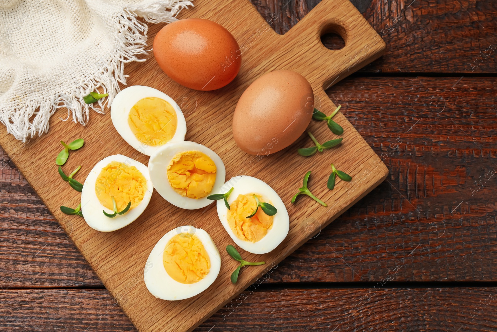 Halves of hard boiled eggs with microgreens on wooden table, top view Photo of Halves of hard boiled eggs with microgreens on wooden table, top view