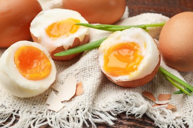 Photo of Soft boiled eggs with green onions on wooden table, closeup