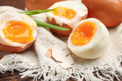 Photo of Soft boiled eggs with green onions on wooden table, closeup