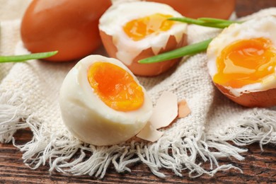 Photo of Soft boiled eggs with green onions on wooden table, closeup