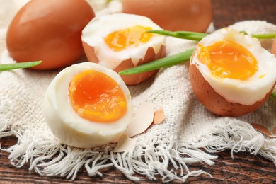 Photo of Soft boiled eggs with green onions on wooden table, closeup