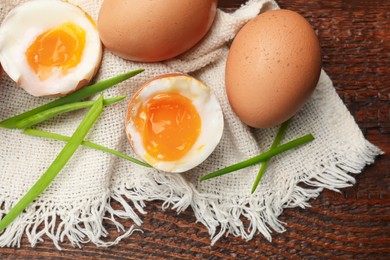 Photo of Soft boiled eggs with green onions on wooden table, flat lay