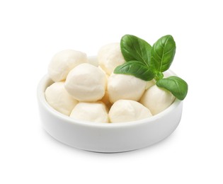 Photo of Tasty mozzarella cheese balls and basil in bowl isolated on white