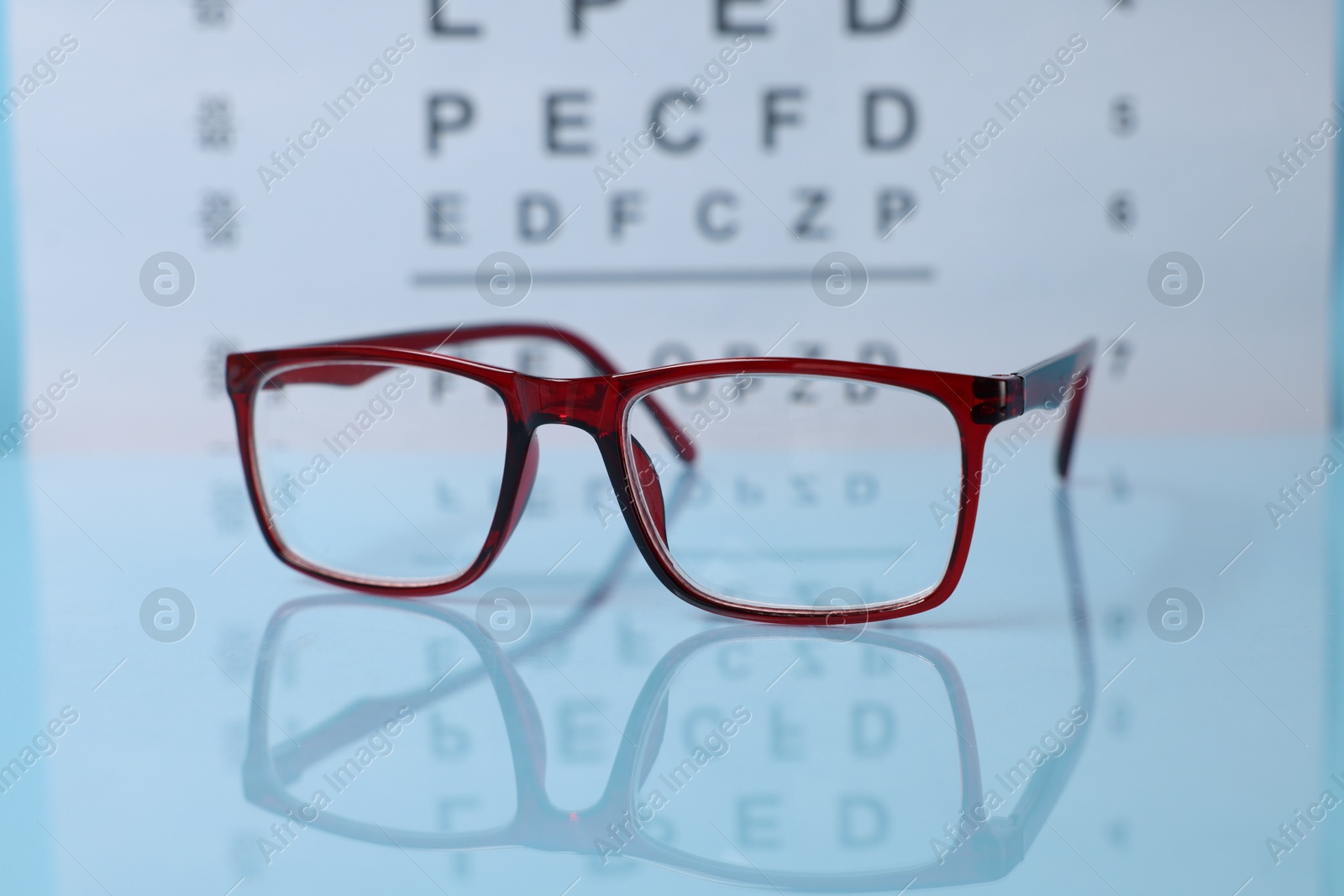 Glasses on light blue table against vision test chart, closeup Photo of Glasses on light blue table against vision test chart, closeup