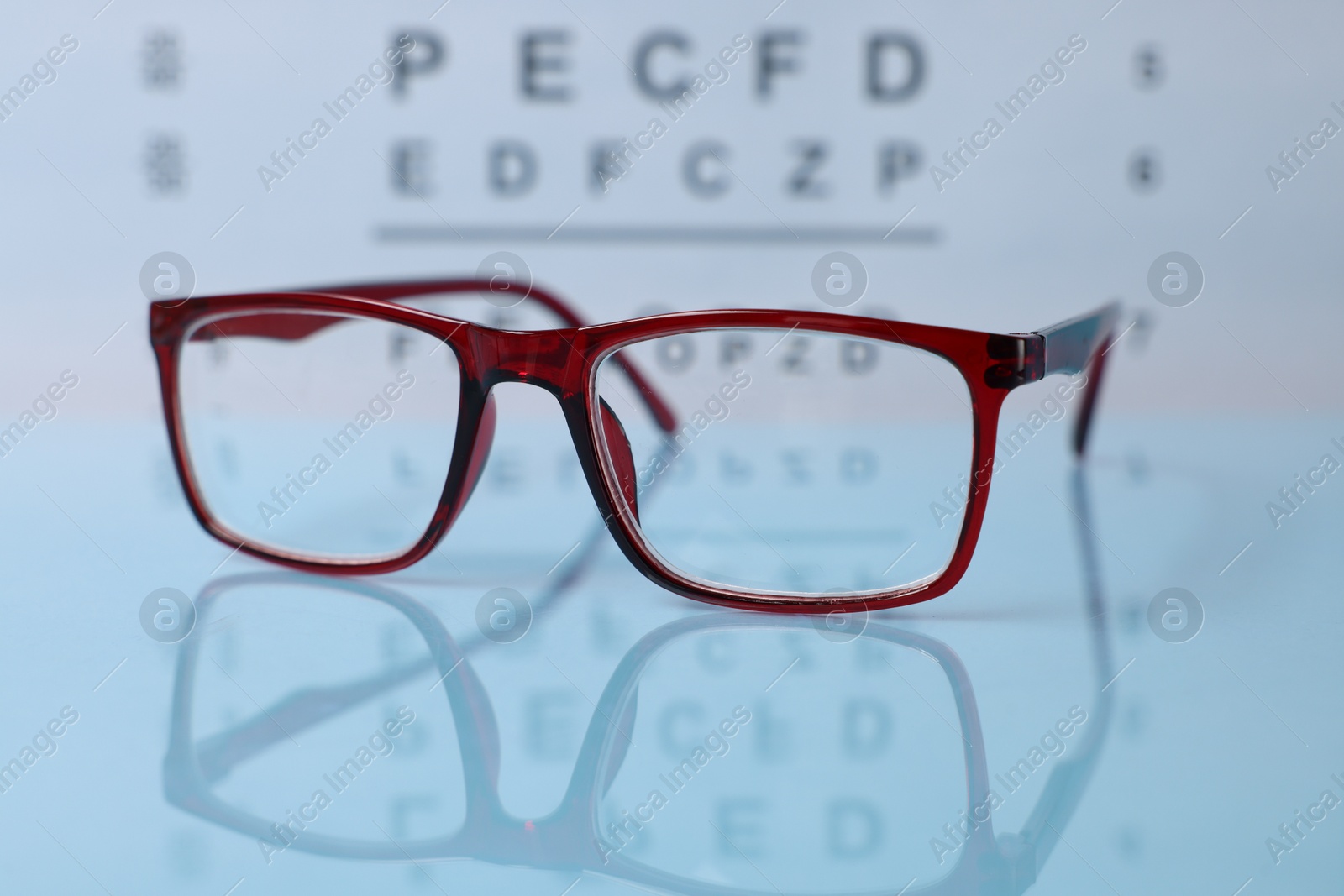 Glasses on light blue table against vision test chart, closeup Photo of Glasses on light blue table against vision test chart, closeup