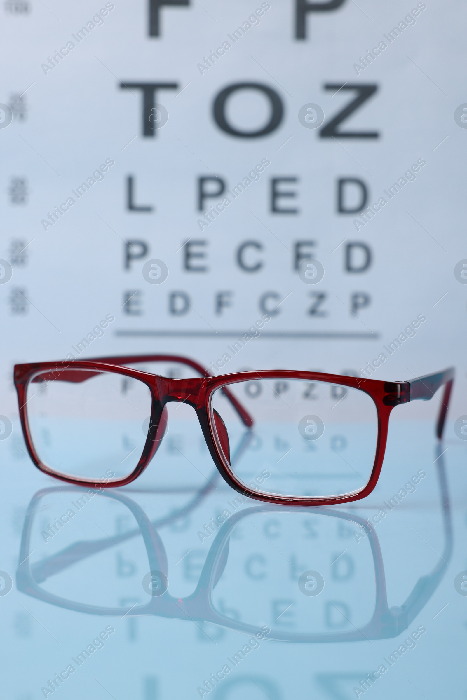 Glasses on light blue table against vision test chart, closeup Photo of Glasses on light blue table against vision test chart, closeup
