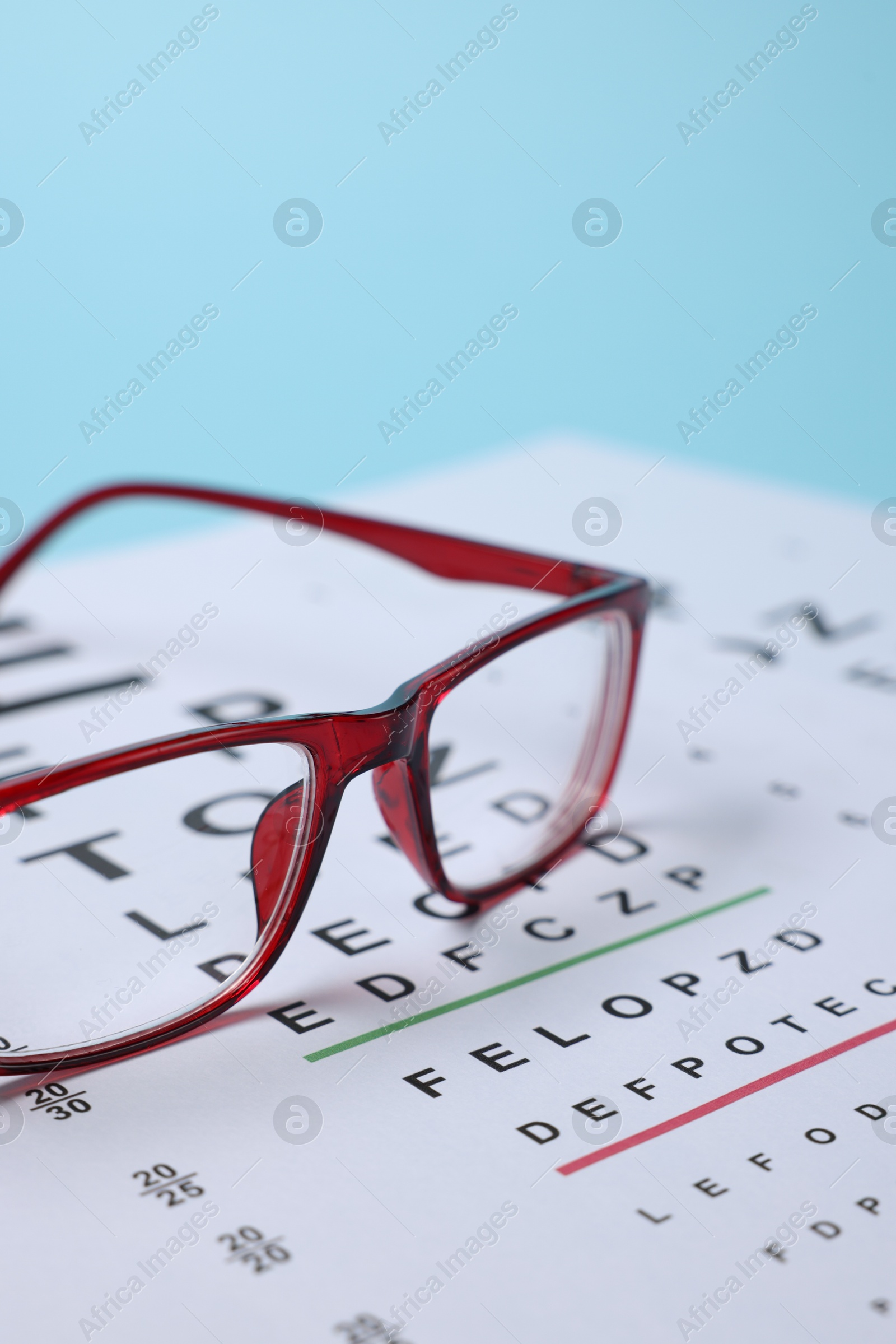 Glasses and vision test chart on light blue background, closeup Photo of Glasses and vision test chart on light blue background, closeup