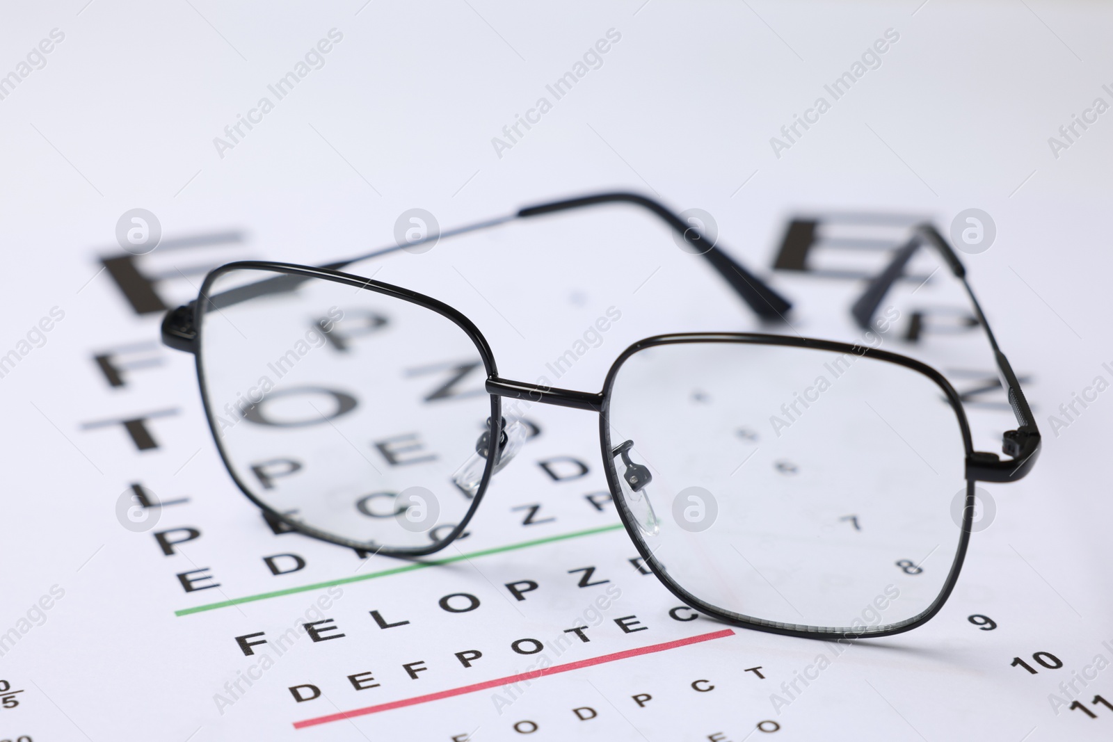 Glasses on vision test charts as background, closeup Photo of Glasses on vision test charts as background, closeup