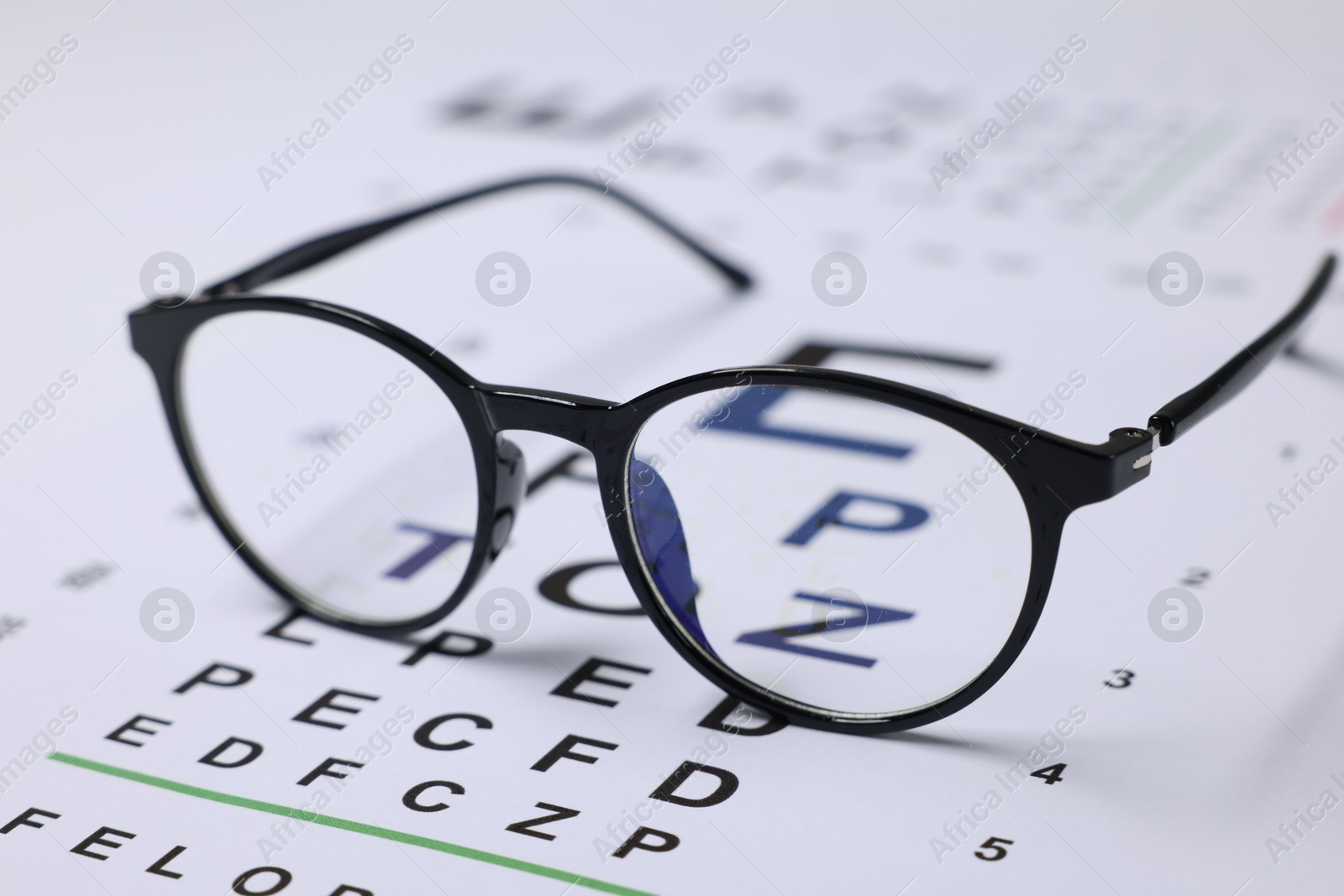 Glasses on vision test charts as background, closeup Photo of Glasses on vision test charts as background, closeup