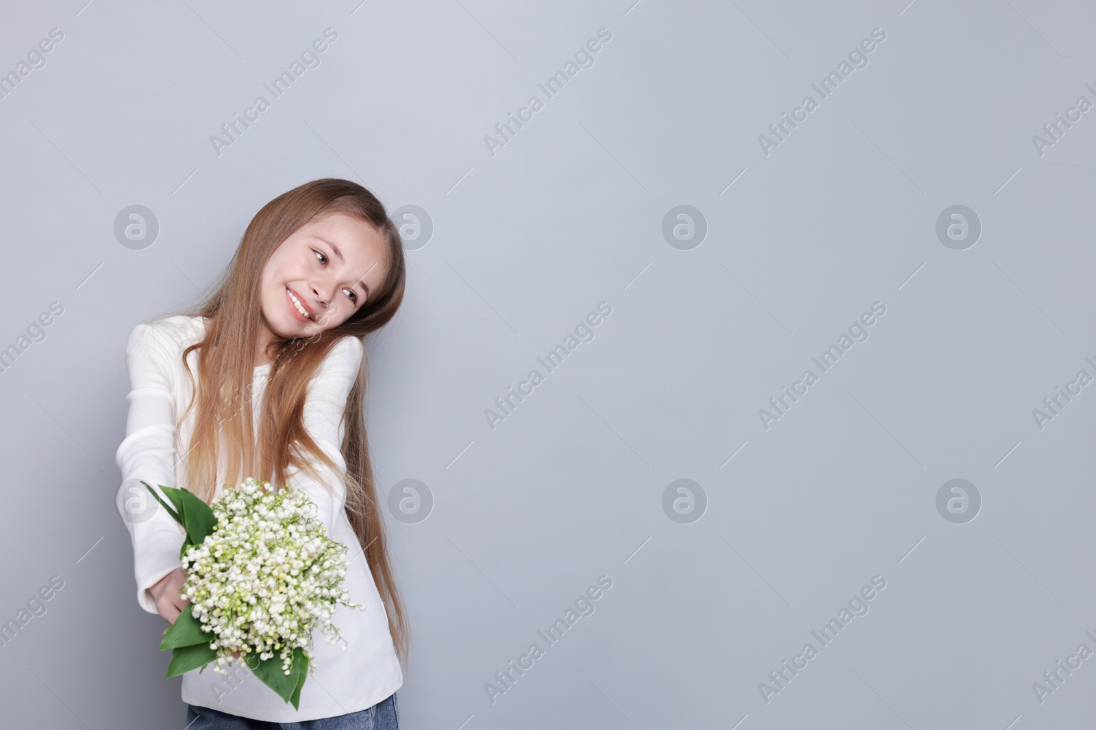 Girl with bouquet of beautiful lily-of-the-valley flowers on light grey background. Space for text Photo of Girl with bouquet of beautiful lily-of-the-valley flowers on light grey background. Space for text